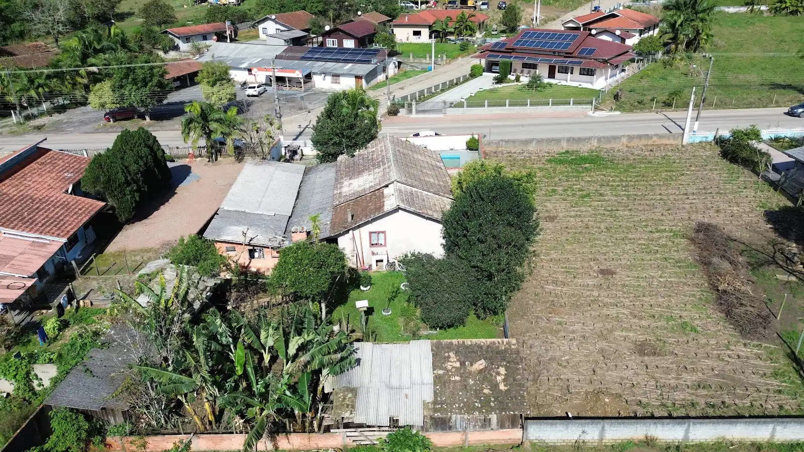 Vista aérea ampla do terreno de 1.000 m² e da rua asfaltada