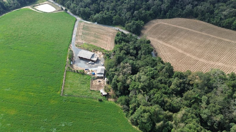 Vista aérea da área rural com edificações ao fundo